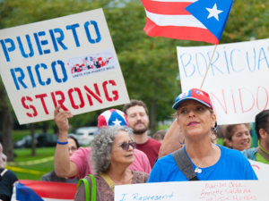 Puerto Rico citizens at a rally with signs and flags