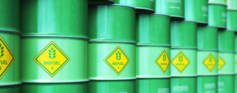 group of green stacked metal biofuel drums or biodiesel barrels in industrial warehouse