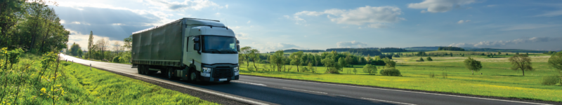 011623 CA Air Regulations_wide White truck driving on the asphalt road in a green rural landscape