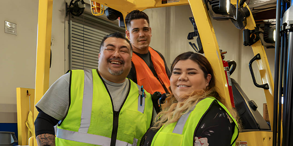 Three warehouse workers with forklift